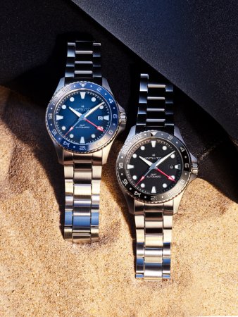 Hamilton Khaki Navy Scuba GMT藍色與黑色面盤腕錶，搭配精鋼鍊帶置於沙地